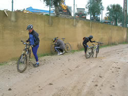 ciclistas a limparem a lama das biciletas