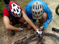 dois ciclistas reparando uma corrente partida